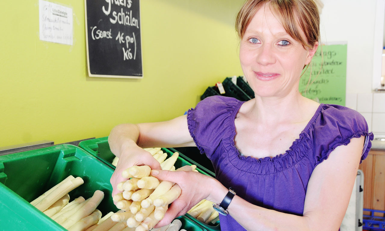 Eine Frau hält frischen weißen Spargel vom Hofladen Lütke Zutelgte in den Händen